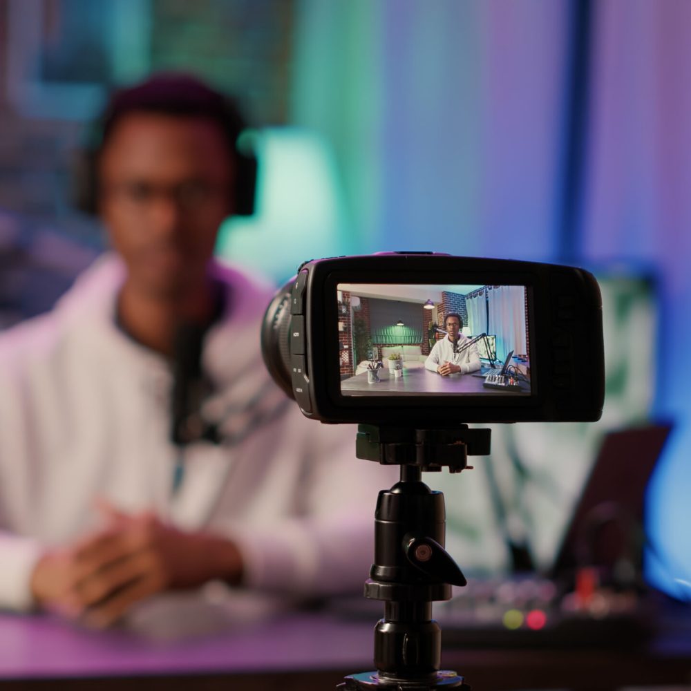 Selective focus on digital video camera screen recording african american content creator streaming live internet show from home. Influencer filming entertainment show for vlog social media post.